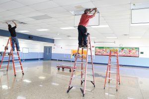 Man installing Litetronics LED Magnetic Retrofits in a middle school.